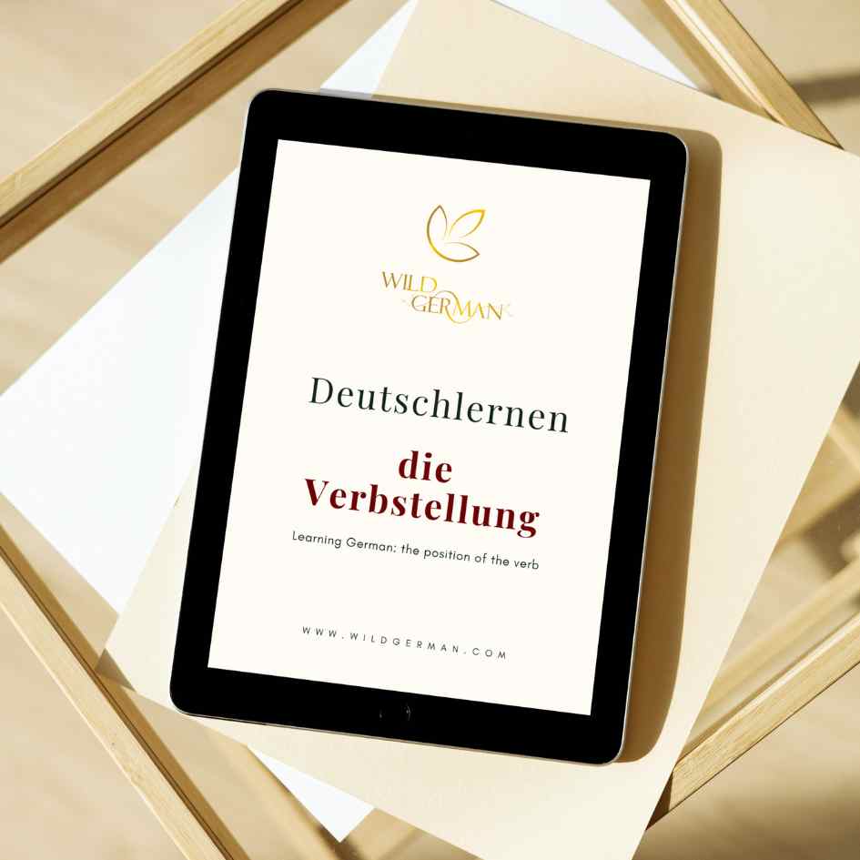Black tablet lies on a side table. Title page of the e-book: Learning German - the verb position can be seen.
